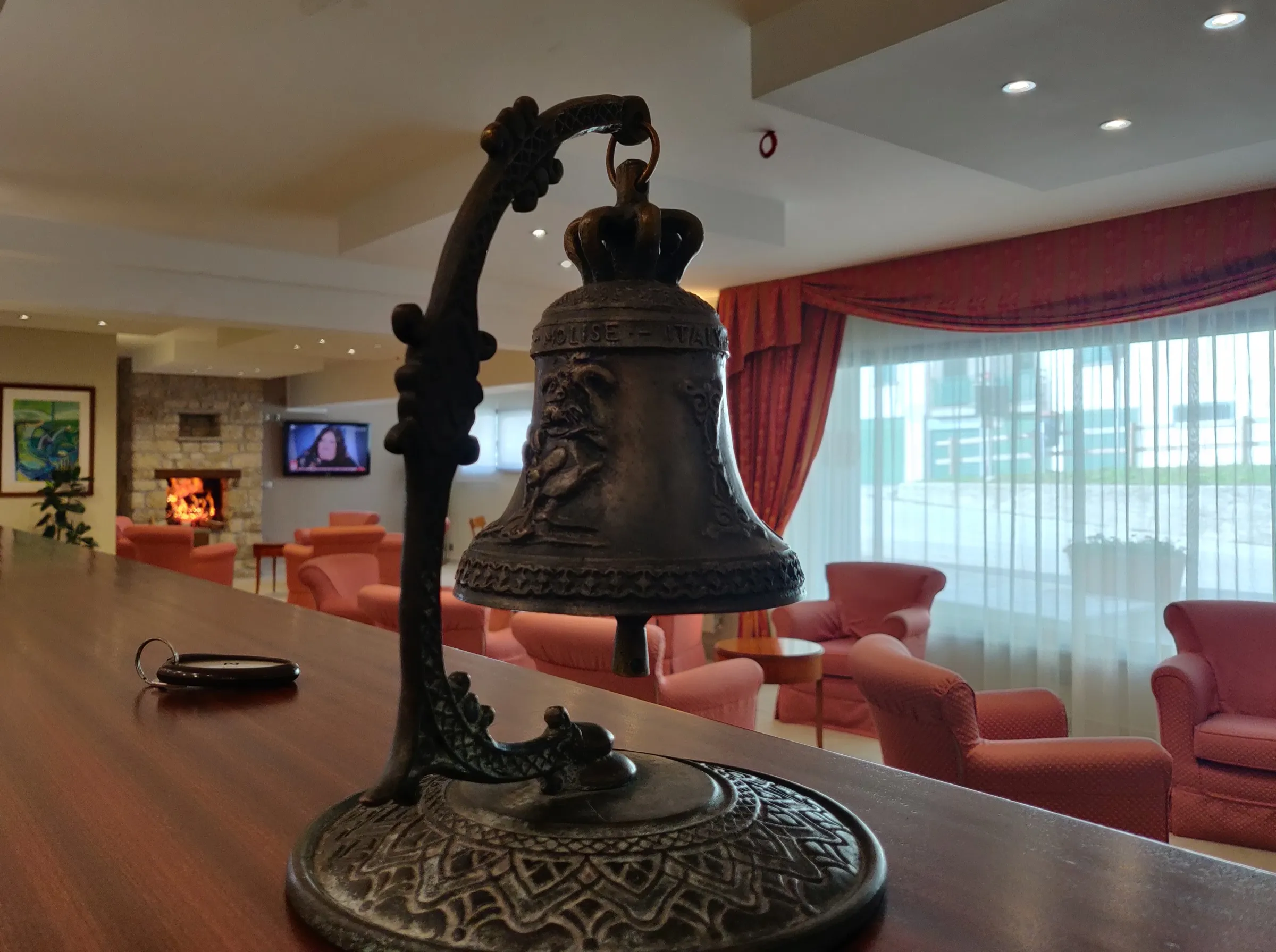 La hall con una campana in bronzo e salottini rossi
