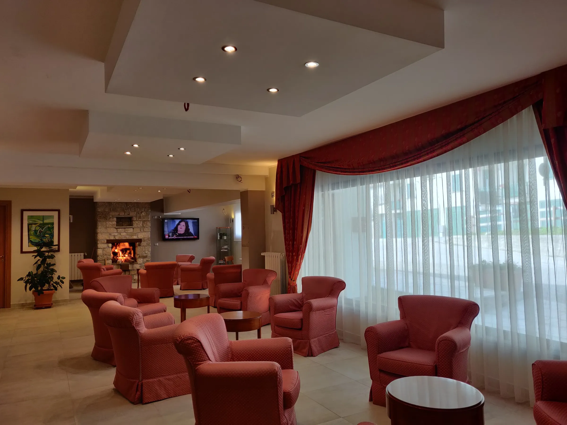 Il salone dell’Albergo Conte Max con poltrone rosse e ampie vetrate